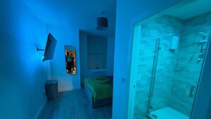 A bedroom with a bed, a mirror, and a shower area. - Apartment in Leeds Close to City Centre (Leeds)