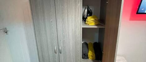 A room with a grey wardrobe, a small table, and a red wall.