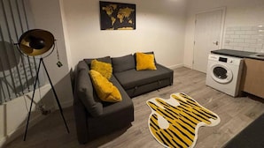 A compact living space with a sofa, a washing machine, and a globe map on the wall. - Apartment in Leeds Close to City Centre (Leeds)