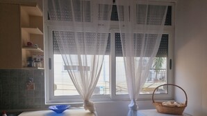 A kitchen with a window, a washing machine, and a blue bowl on the counter. - Mihal Popi Apartment (Tirana)