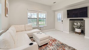 Een moderne woonkamer met een witte bank, een flatscreen televisie en een open haard.