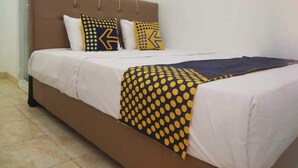 A bed with a brown headboard, white bedding, and patterned pillows. - SPOT ON 93478 Amanda Residence Syariah (Palembang)