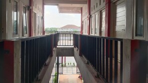 A corridor with a balcony, leading to a building with a red and white facade. - SPOT ON 93478 Amanda Residence Syariah (Palembang)