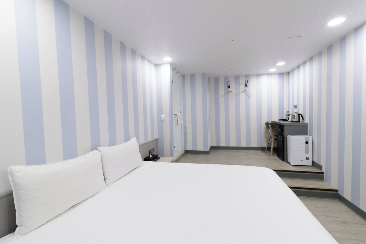 Une chambre d’hôtel avec un grand lit, un bureau et une kitchenette.
