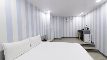 Ein Hotelzimmer mit einem großen Bett, einem Schreibtisch und einer Küchenzeile.
