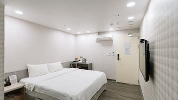 A hotel room with a bed, bedside table, and a desk with a chair.