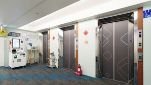 Elevatorområde med to elevatorer, en brandslukker og en selvbetjeningscheck-in kiosk.