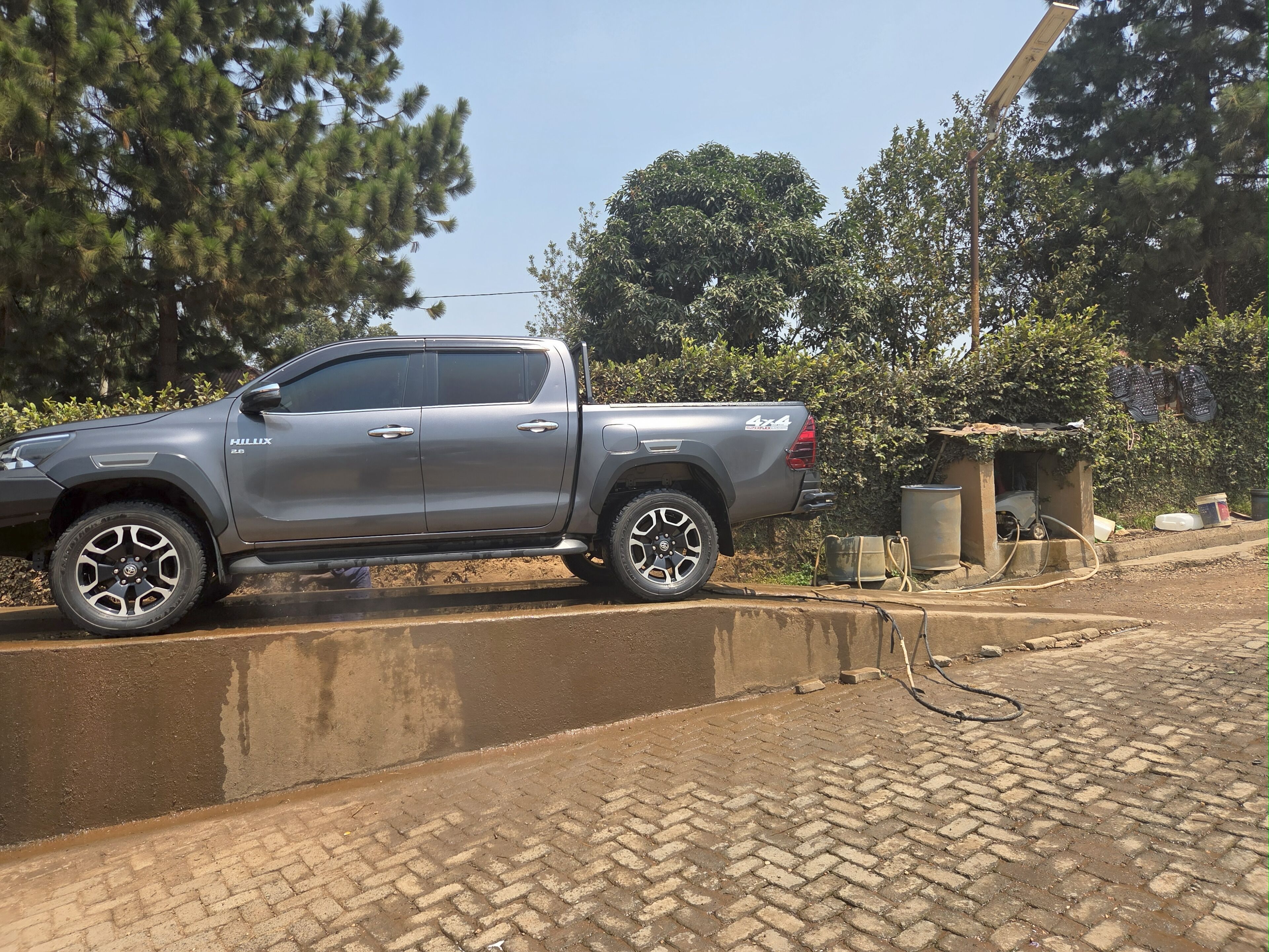 A silver pickup truck parked on a brick-paved area with a small structure in the background.
