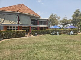 Un edificio con techo de tejas, vestíbulo cubierto y un patio con mobiliario exterior.