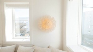 A room with a large window, a white wall, and a textured spherical light fixture.