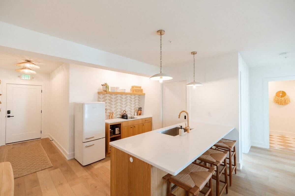 Een moderne keuken met een centraal eiland, houten kastjes en hanglampen.