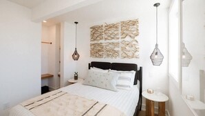 Ein Schlafzimmer mit Bett, Nachttischen, Wanddekoration und einer Pendelleuchte.