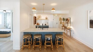 Una cocina moderna con una isla central, taburetes de bar e iluminación colgante.