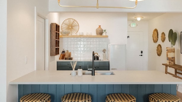 Una cocina moderna con una isla central, taburetes de bar y un elemento decorativo en la pared.
