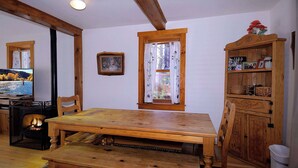 A cozy room with a wooden dining table, chairs, a fireplace, a television, and a window with curtains. - "Wild Iris" Historic Home in downtown CB, Dog Friendly! (Crested Butte)