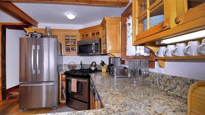 A kitchen with stainless steel appliances, wooden cabinets, and a granite countertop. - "Wild Iris" Historic Home in downtown CB, Dog Friendly! (Crested Butte)