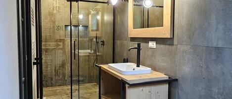 A modern bathroom with a glass shower, a wooden vanity, and a large mirror.