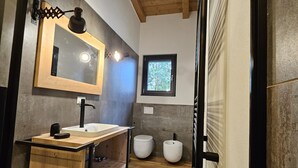 A modern bathroom with a wooden vanity, a large mirror, a ceiling light, and a window. - GiardinidiEva (San Floriano del Collio)