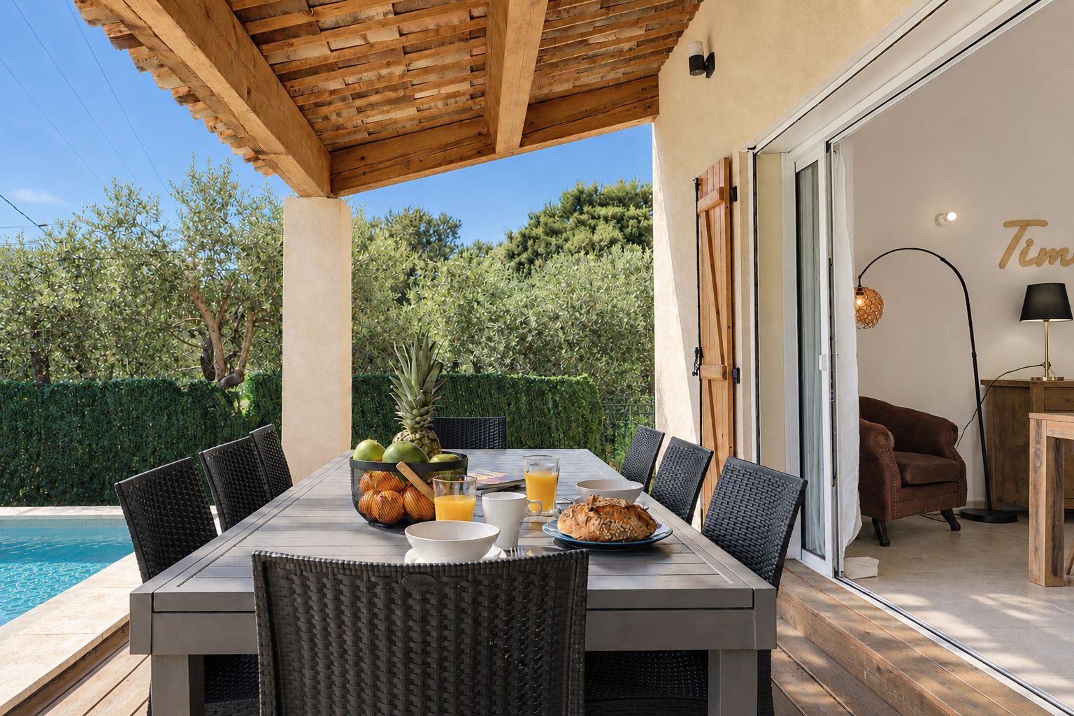 A dining area with a pool view, outdoor seating, and a modern interior.