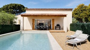 Une piscine avec un espace patio, un coin salon couvert et une vue sur le paysage environnant.