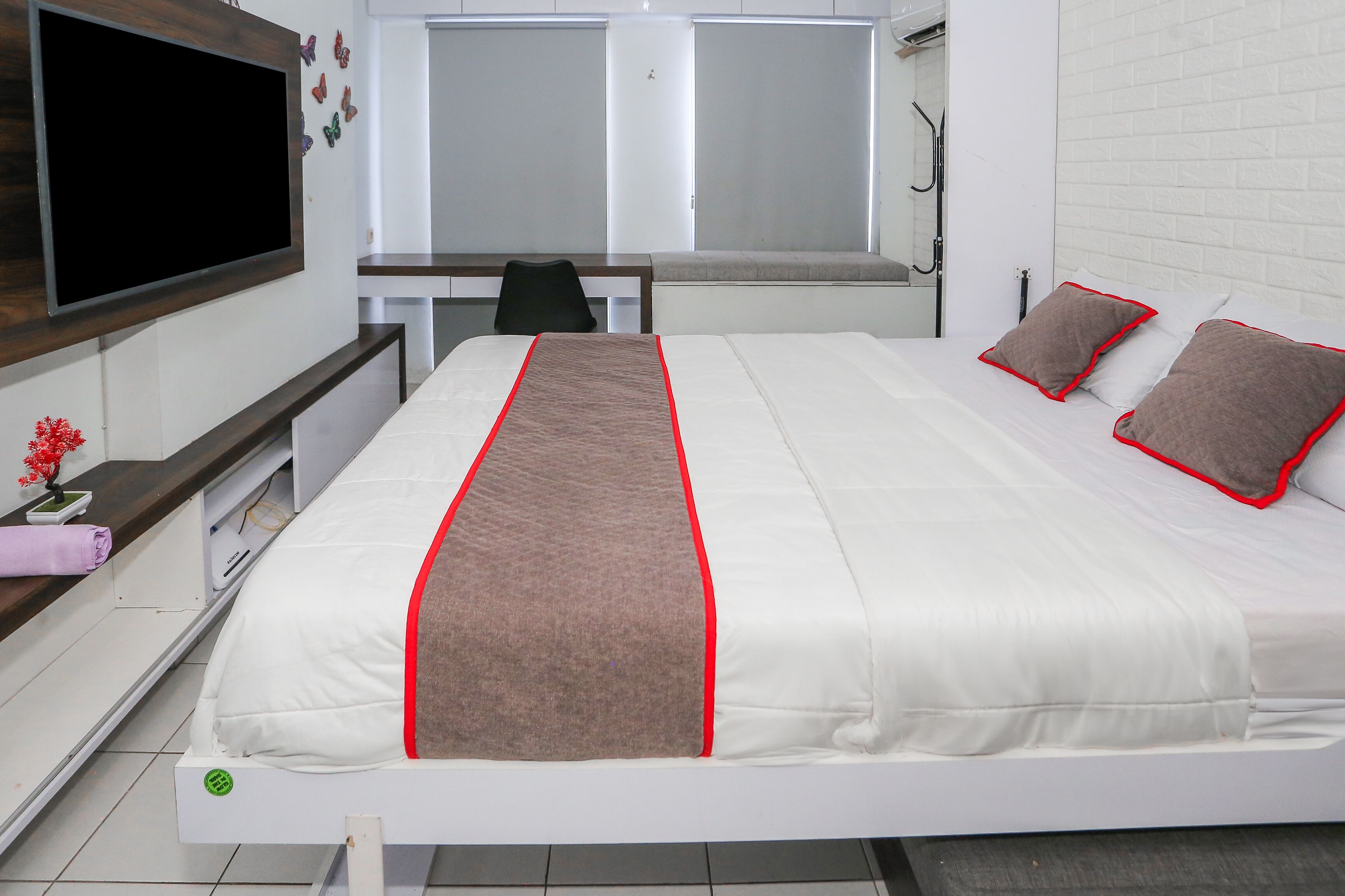 Une chambre d’hôtel équipée d’un lit, d’un bureau, d’une chaise et d’un téléviseur fixé au mur.