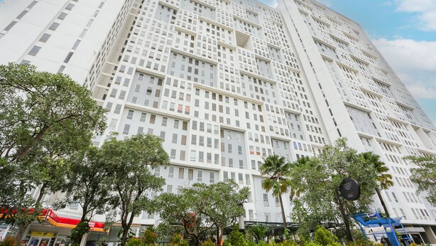 A high-rise building with a grid-like facade, surrounded by trees and a clear sky. - Capital O 93490 Yubi Room Patraland  (Bekasi)