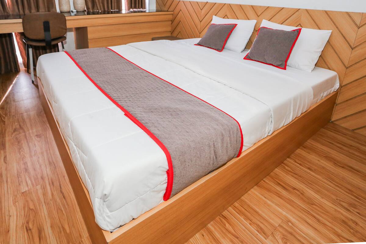 Un lit bien fait avec une tête de lit en bois, un bureau avec une chaise et un plancher en bois.