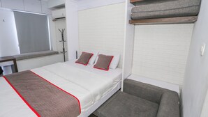 A bedroom with a bed, a bench, and a wardrobe. - Capital O 93490 Yubi Room Patraland  (Bekasi)