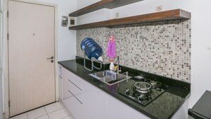 A kitchen with a tiled backsplash, a sink, a stove, and a door. - Capital O 93490 Yubi Room Patraland  (Bekasi)