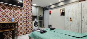 Une pièce comprenant un lit, un lave-linge, une armoire et une petite table.