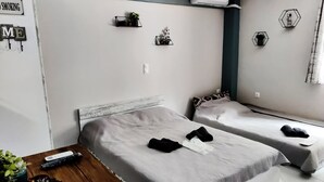 Quarto moderno com duas camas, piso de madeira e uma pequena mesa com uma planta.