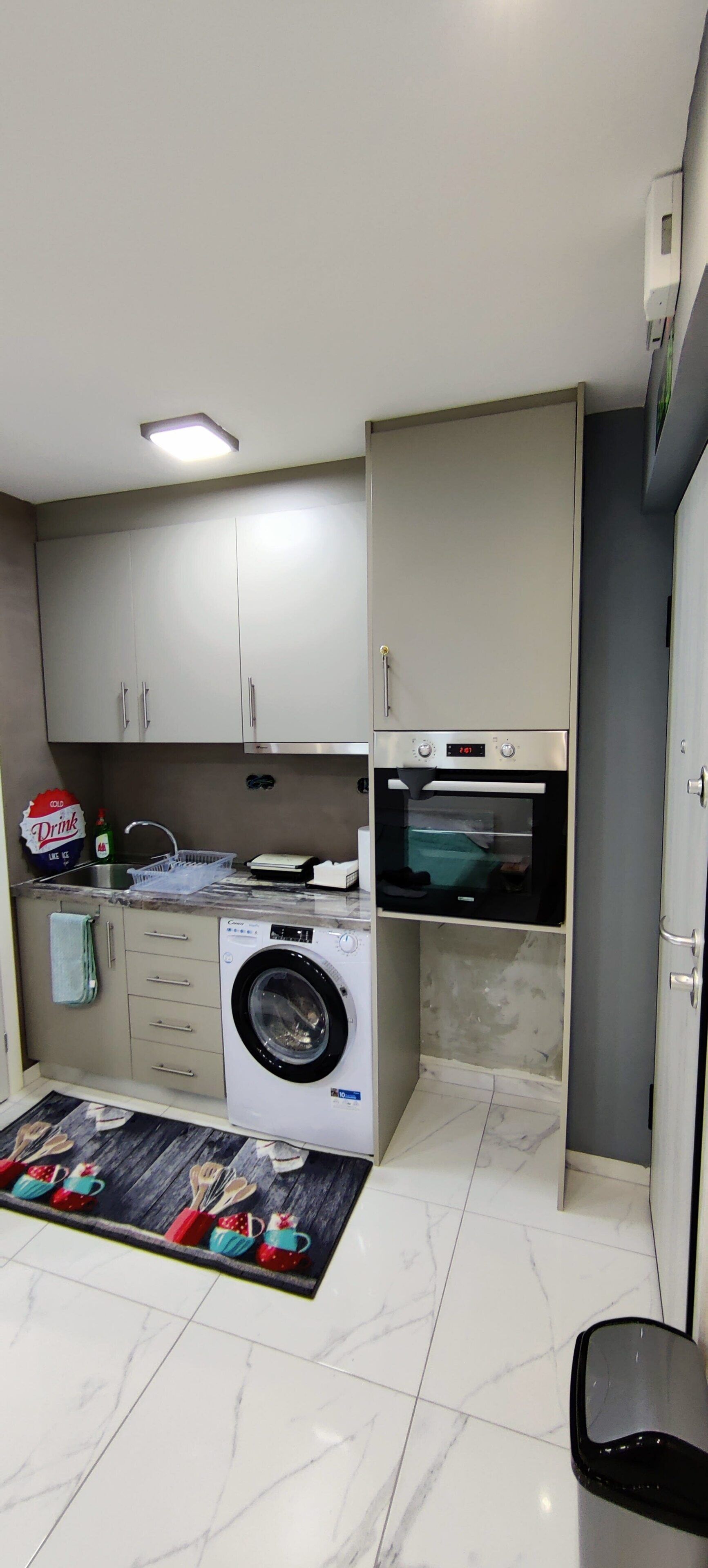 A compact kitchen with a washing machine, a microwave, and a sink.