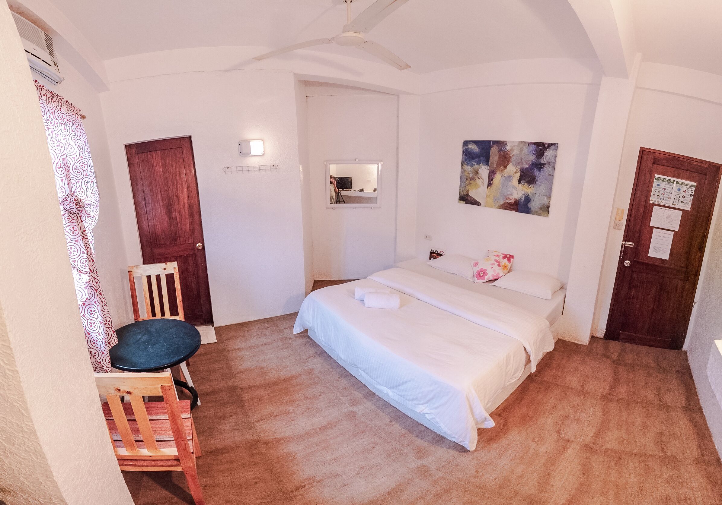 A bedroom with a bed, a chair, a wooden door, and a ceiling fan.