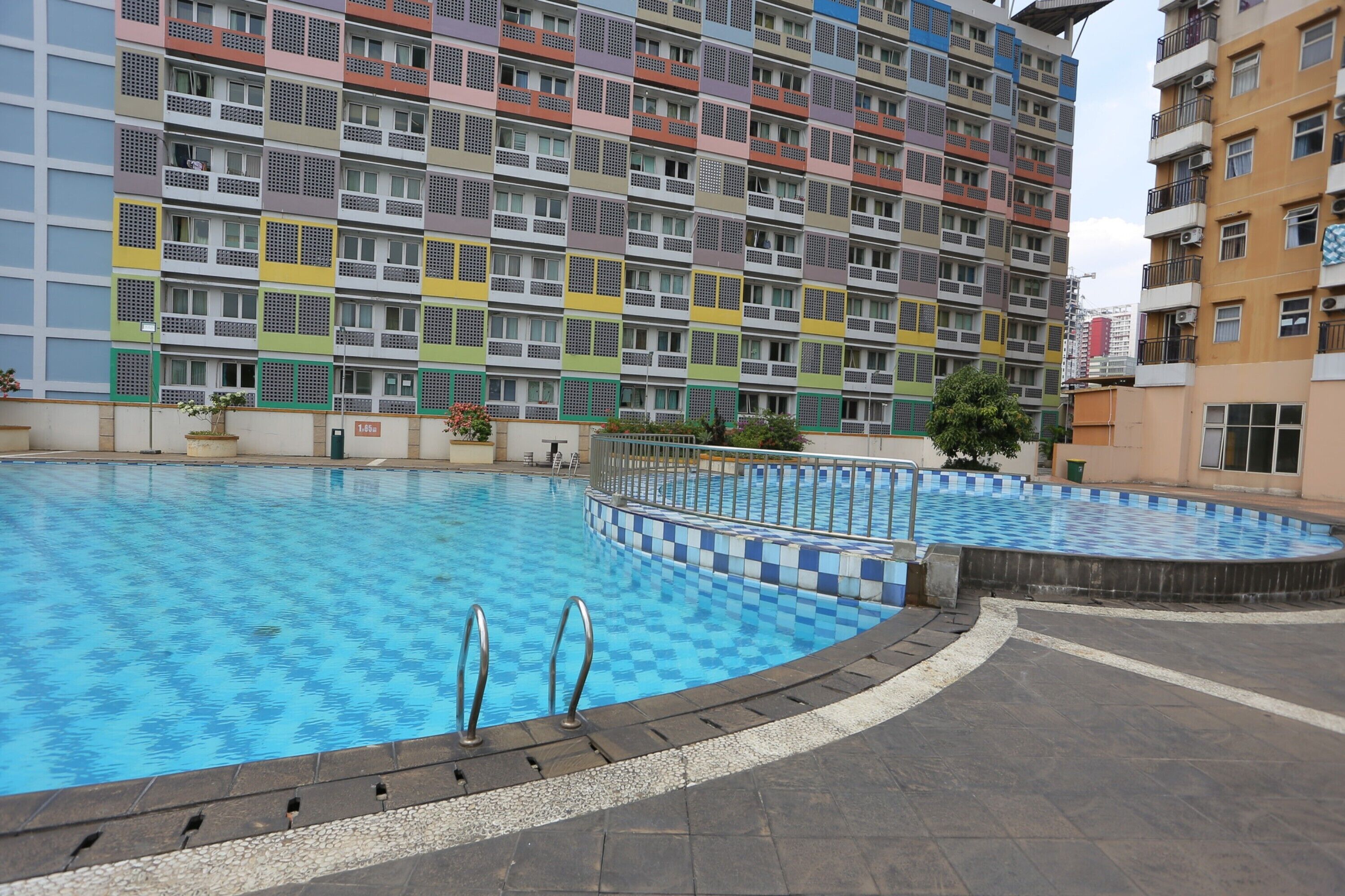 A swimming pool area with a multi-story building in the background.