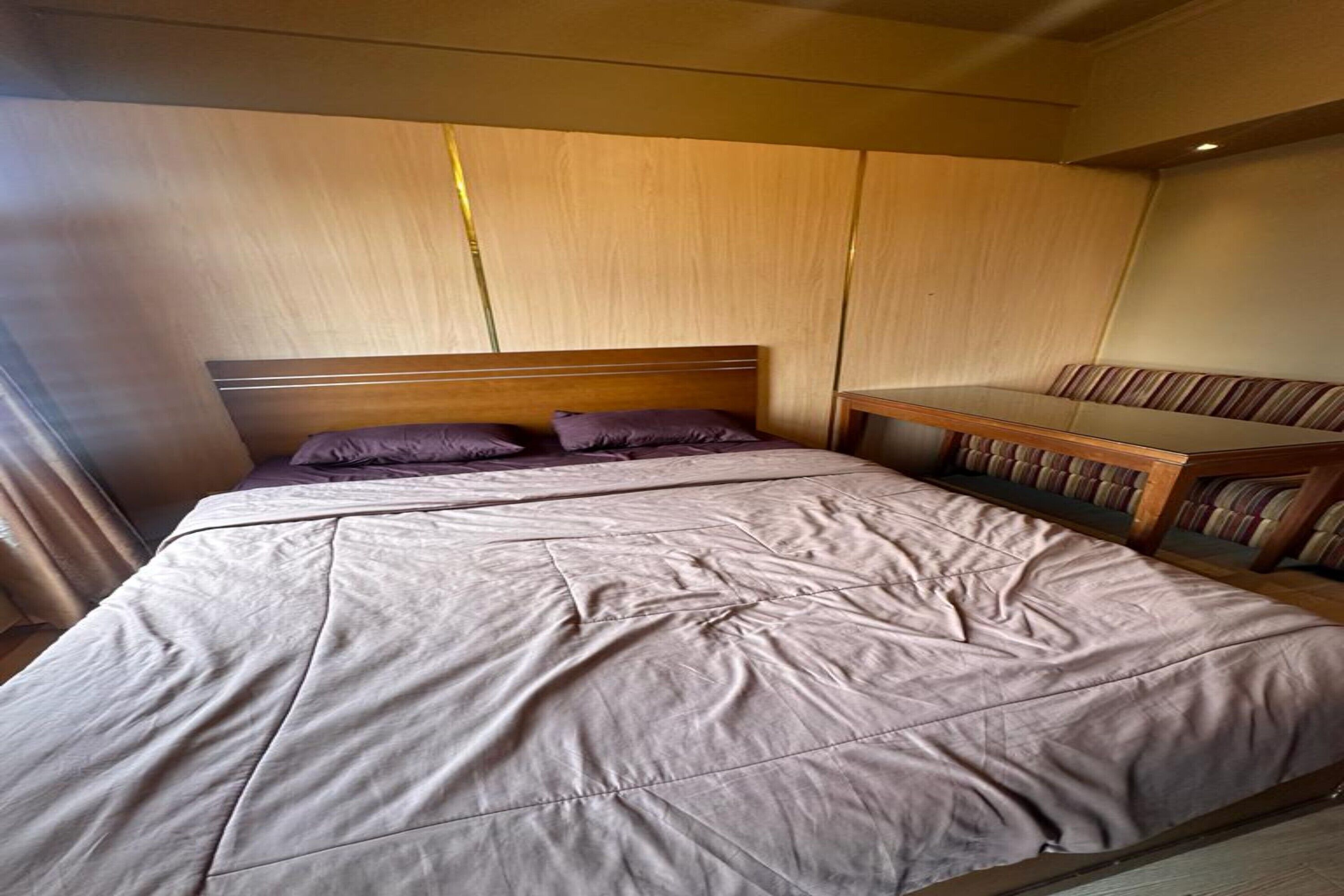 A bedroom with a large bed, a wooden headboard, and a bench with striped cushions.