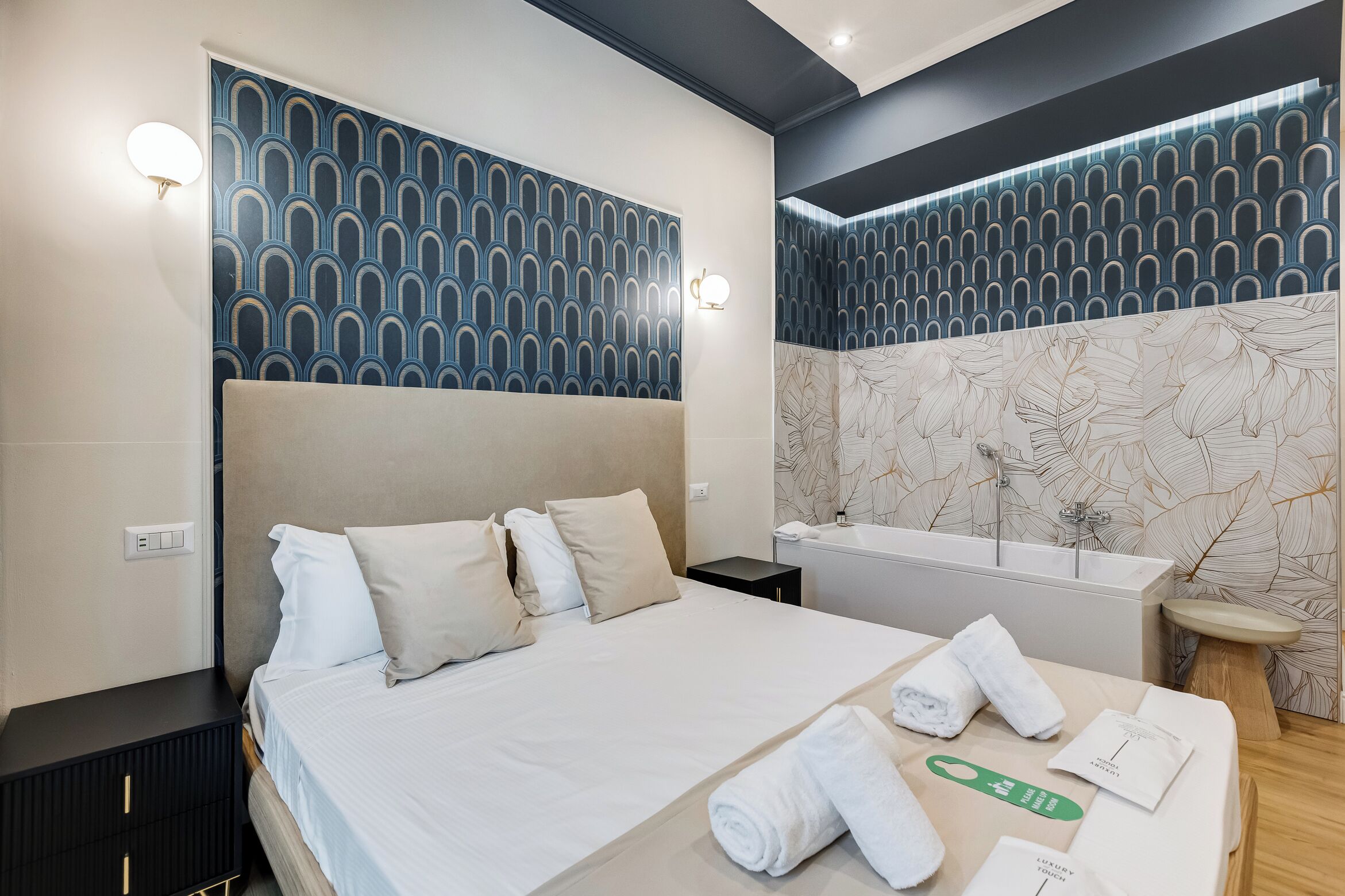 Habitación de hotel con una cama grande, un baño con bañera y un tocador con espejo.