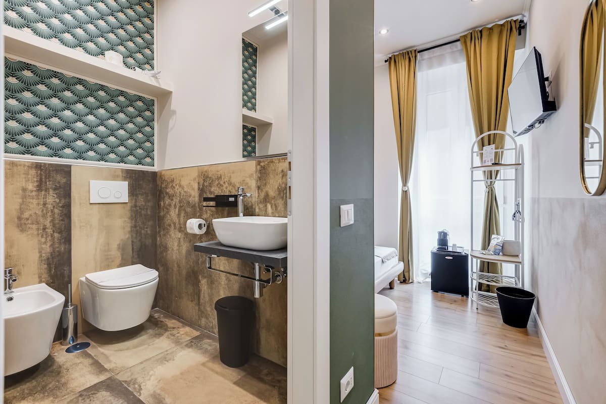 A modern bathroom with a white sink, toilet, and bidet, a mirror, and a shower area with a glass door.