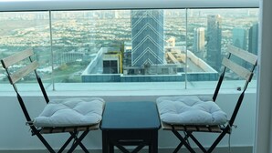 A balcony with two chairs and a table, offering a city view. - Hawana Premium Hostel (Dubai)