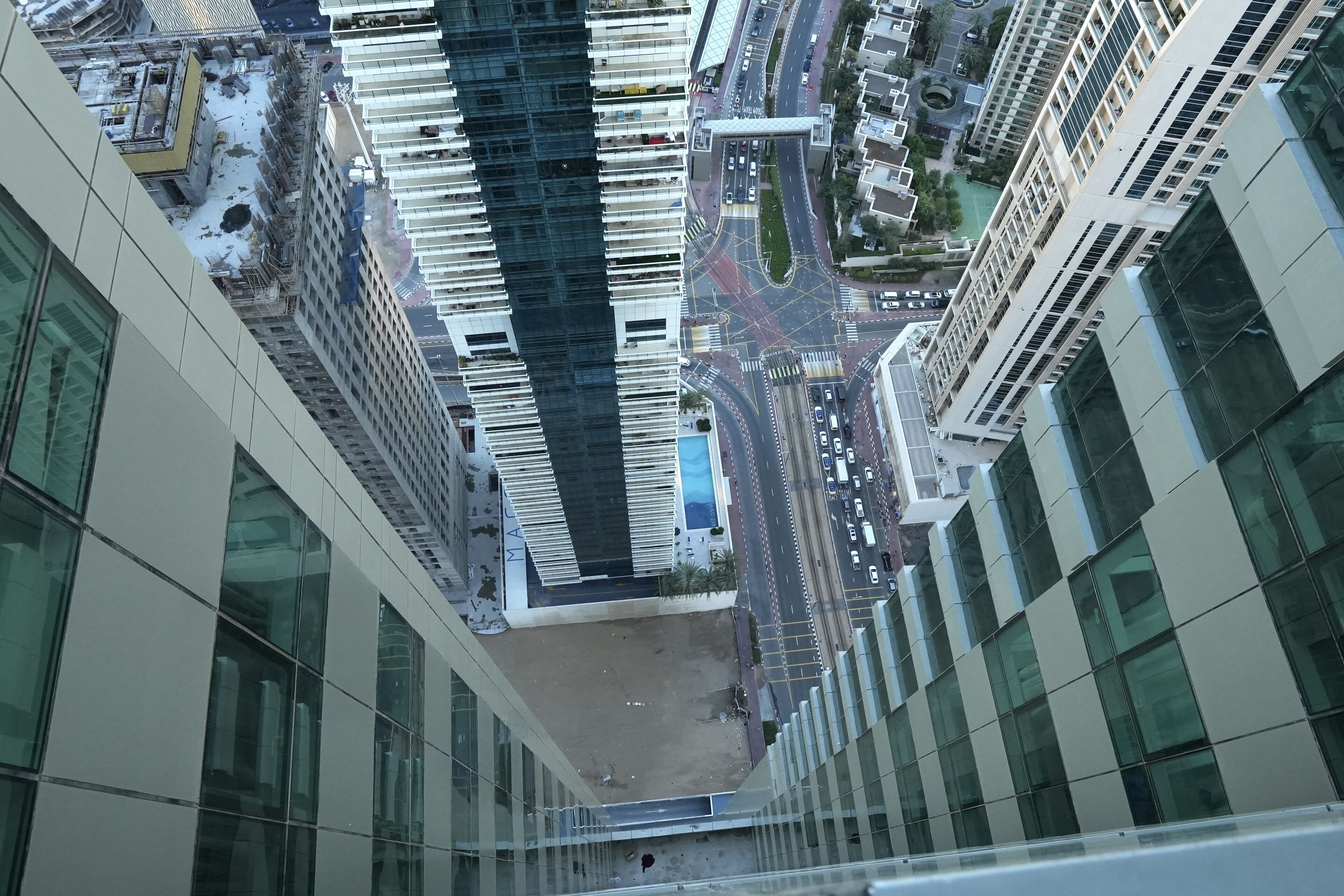 A high-rise building with a modern glass facade, a central courtyard, and a busy street with cars and pedestrians.