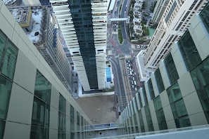 Un edificio de gran altura con fachada de vidrio moderna, un patio central y una calle concurrida con coches y peatones.