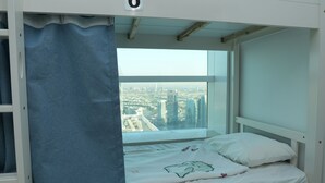 A bunk bed with a city view, a curtain, and a number '6' on the wall. - Hawana Premium Hostel (Dubai)