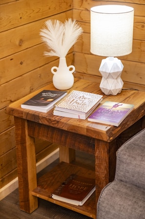 A wooden table with a white vase, a feather, and books.