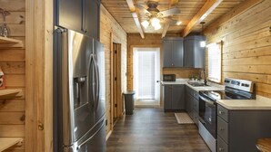Una cocina compacta con paredes de madera, un refrigerador de acero inoxidable, un microondas y una estufa.