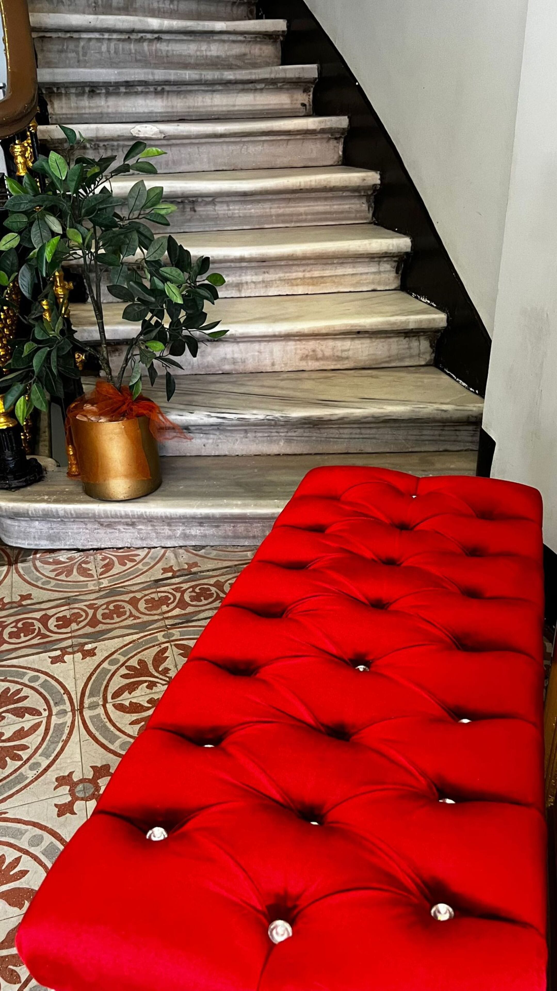 Un escalier avec un banc rouge à capitons au bas.