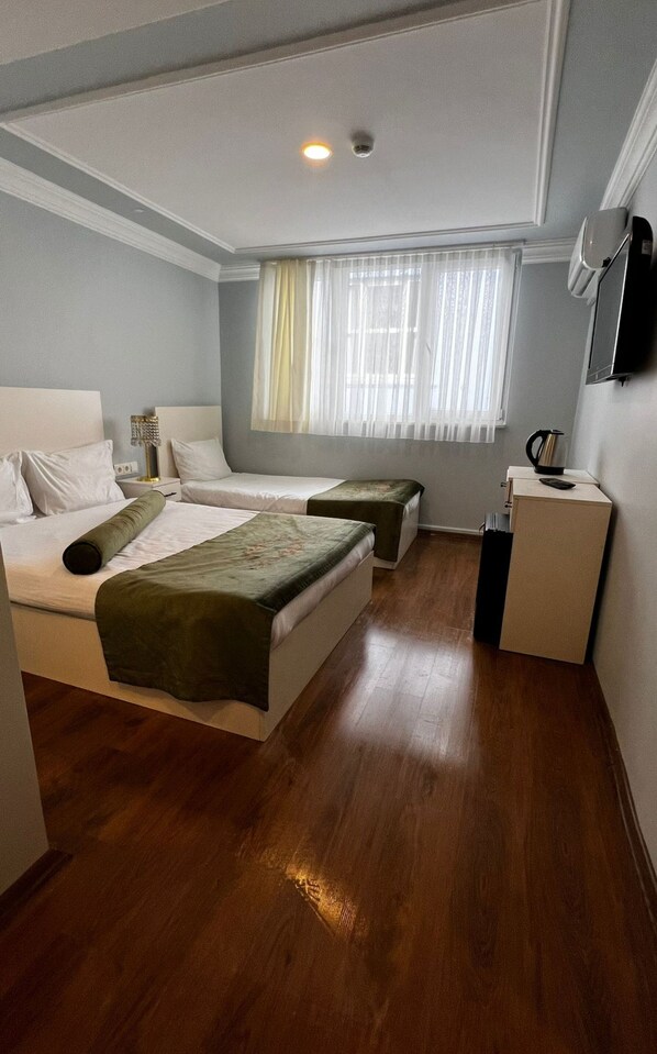 Relax in this serene space with a large bed, a smaller bed, and a bedside table, perfect for a comfortable stay.