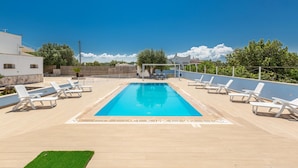 En rektangulär swimmingpool med ett kaklat poolområde, omgiven av vita solstolar.