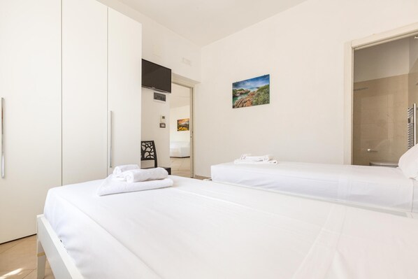 Une chambre d’hôtel avec deux lits, une armoire, une télévision et un espace douche.