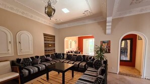 Een ruime woonkamer met een hoekbank, een bijzettafeltje en een decoratief vloerkleed.