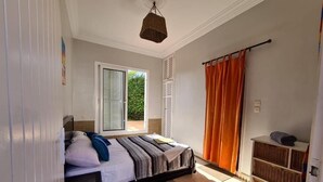 Een slaapkamer met een bed, een raam, een deur, een plank en een hanglamp.