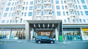 A modern hotel with a covered entrance, multiple balconies, and storefronts including a visible restaurant. - Hotel O Tokyo Riverside (Teluknaga)